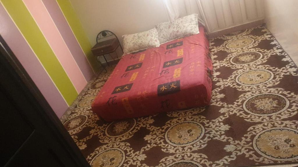 a bed with a red comforter in a bedroom at hay massira 4 in Dakhla