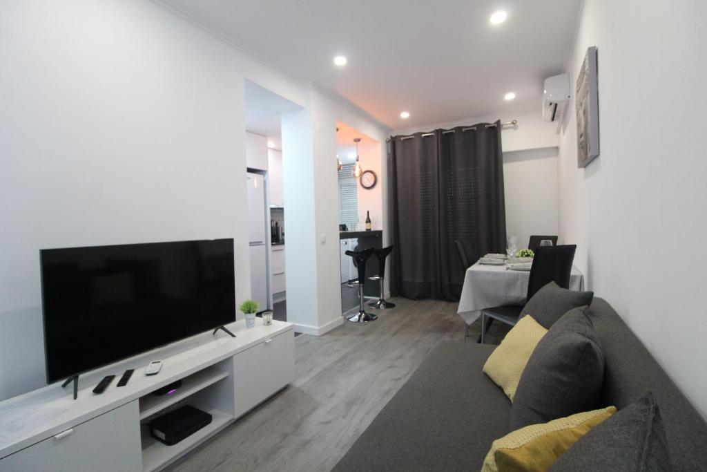 a living room with a couch and a flat screen tv at Varanda do Bonfim in Setúbal