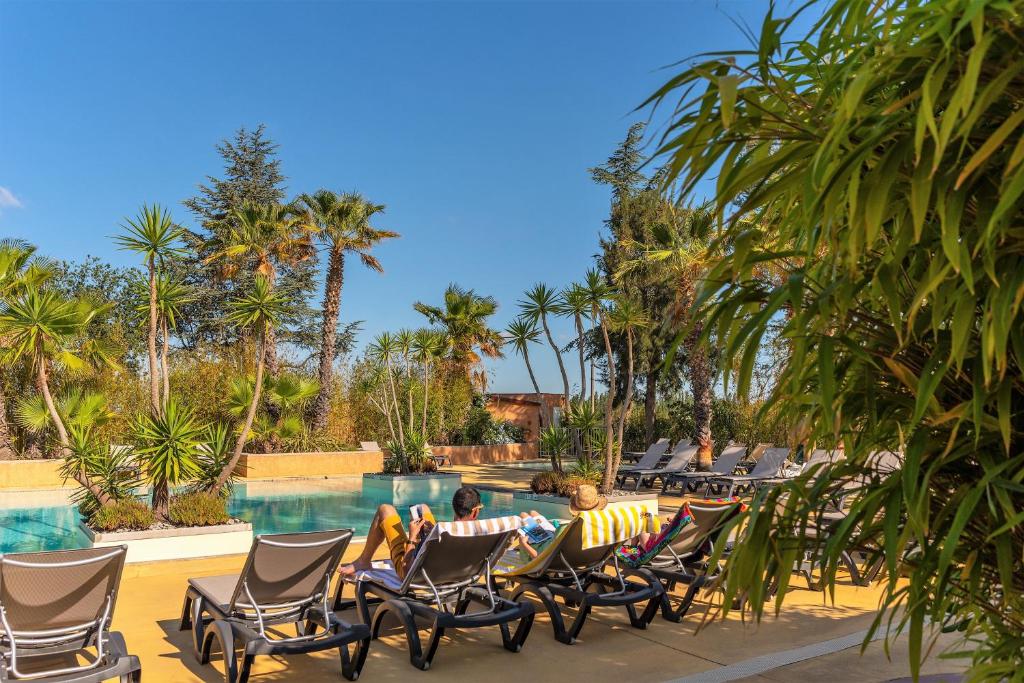 濱海阿熱萊斯的住宿－魔松樹露營酒店，一群人坐在游泳池边的椅子上