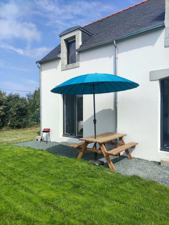 - une table de pique-nique avec un parasol bleu en face d'une maison dans l'établissement maison neuve 4 ou 5 personnes Kerguen, à Plobannalec-Lesconil
