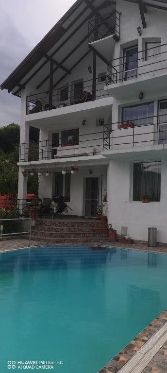 a house with a swimming pool in front of a building at LaBebe - Vidraru in Arefu