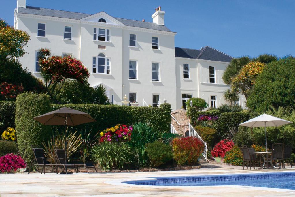 a large white building with a pool in front of it at La Haule Manor in Saint Aubin