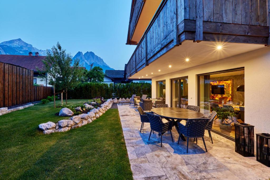 um pátio com uma mesa e cadeiras num quintal em Private Spa & Garden Alpi em Garmisch-Partenkirchen