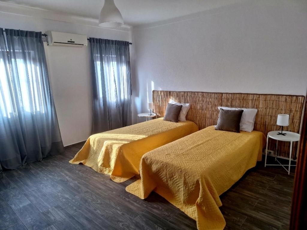 een hotelkamer met 2 bedden met gele lakens bij Morgado Guest House in Ervedal