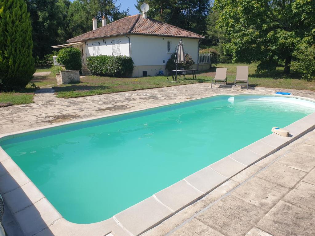 ein großer blauer Pool mit einem Haus im Hintergrund in der Unterkunft Charmante propriété, piscine, Zoo Beauval, Châteaux Loire in Selles-sur-Cher