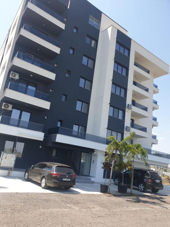 two cars parked in a parking lot in front of a building at Sun up Mamaia nord in Năvodari