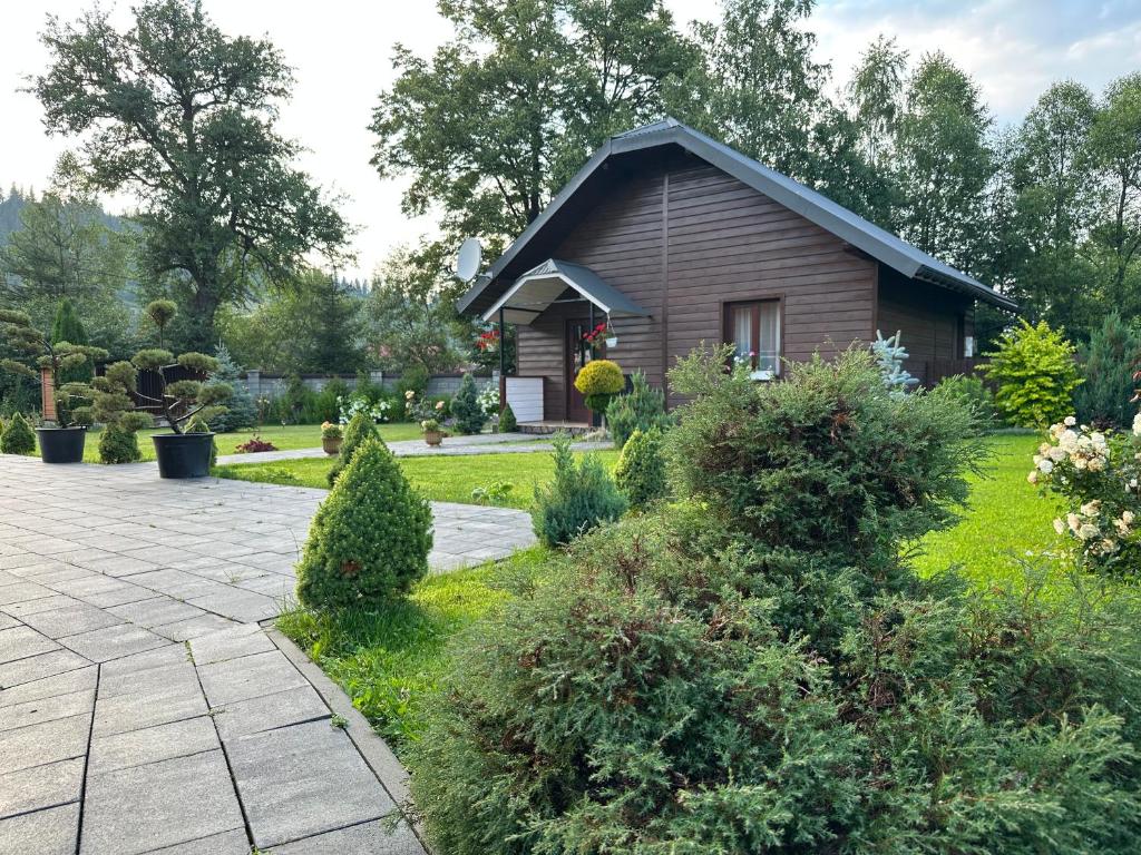 uma pequena casa de madeira com um jardim em frente em Краєвид em Slavske