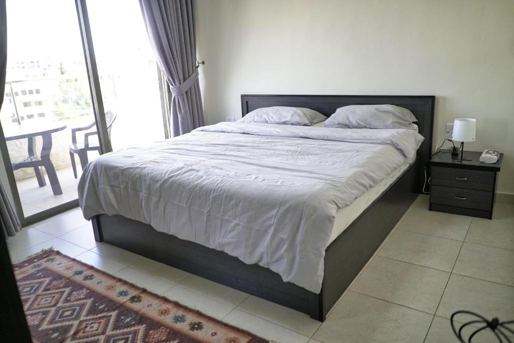 duże łóżko w sypialni z dużym oknem w obiekcie شقة فاخرة و واسعة من 4 غرف مع وسائل الراحة الحديثة Spacious 4-Room Apartment with Modern Amenities w mieście Amman