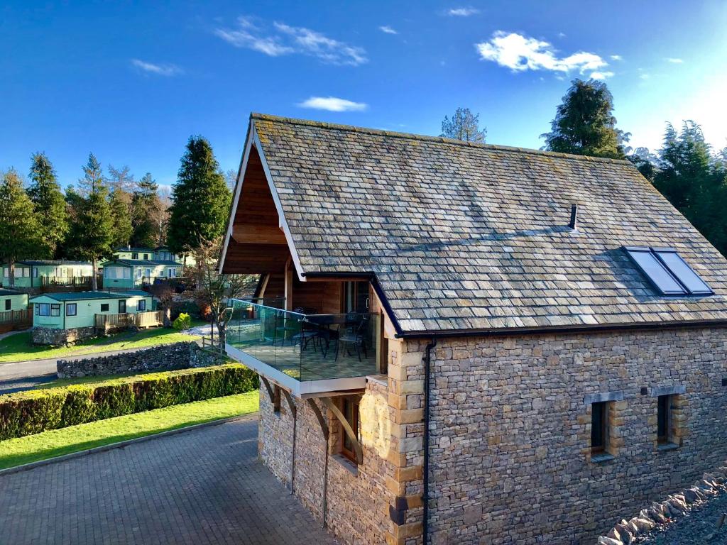 a large brick house with a roof with a deck at Aikbeck Lodge in Penrith