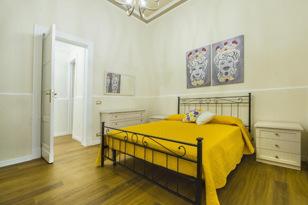 a bedroom with a bed with a yellow blanket at Appartamento Martoglio - Casa Vacanze - in Catania
