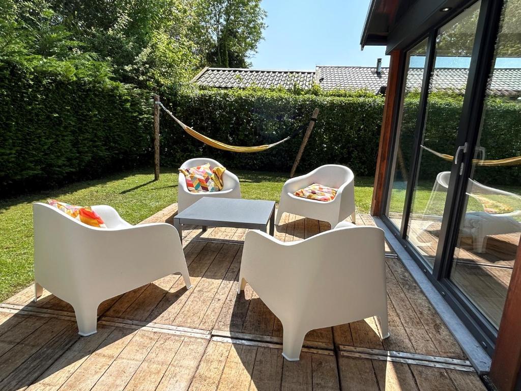 eine Terrasse mit weißen Stühlen und einem Tisch in der Unterkunft Oosterschelde Lodge met veel privacy en dicht bij het water in Scherpenisse