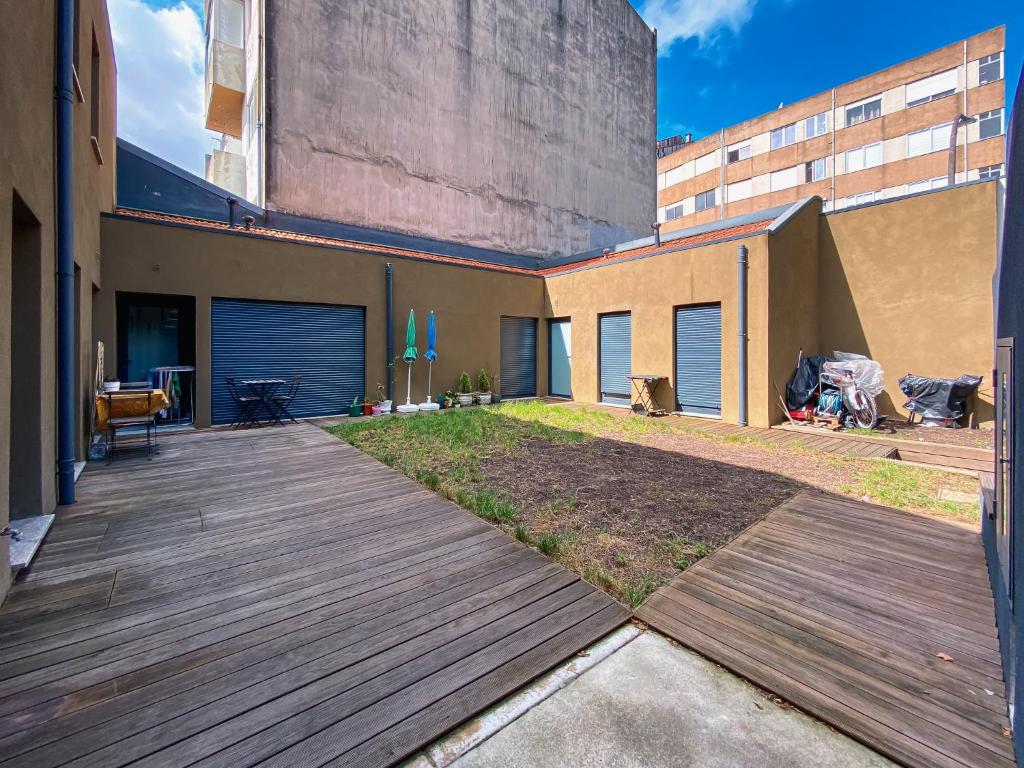 un patio trasero con una terraza de madera junto a un edificio en Casas S. Dinis, en Oporto