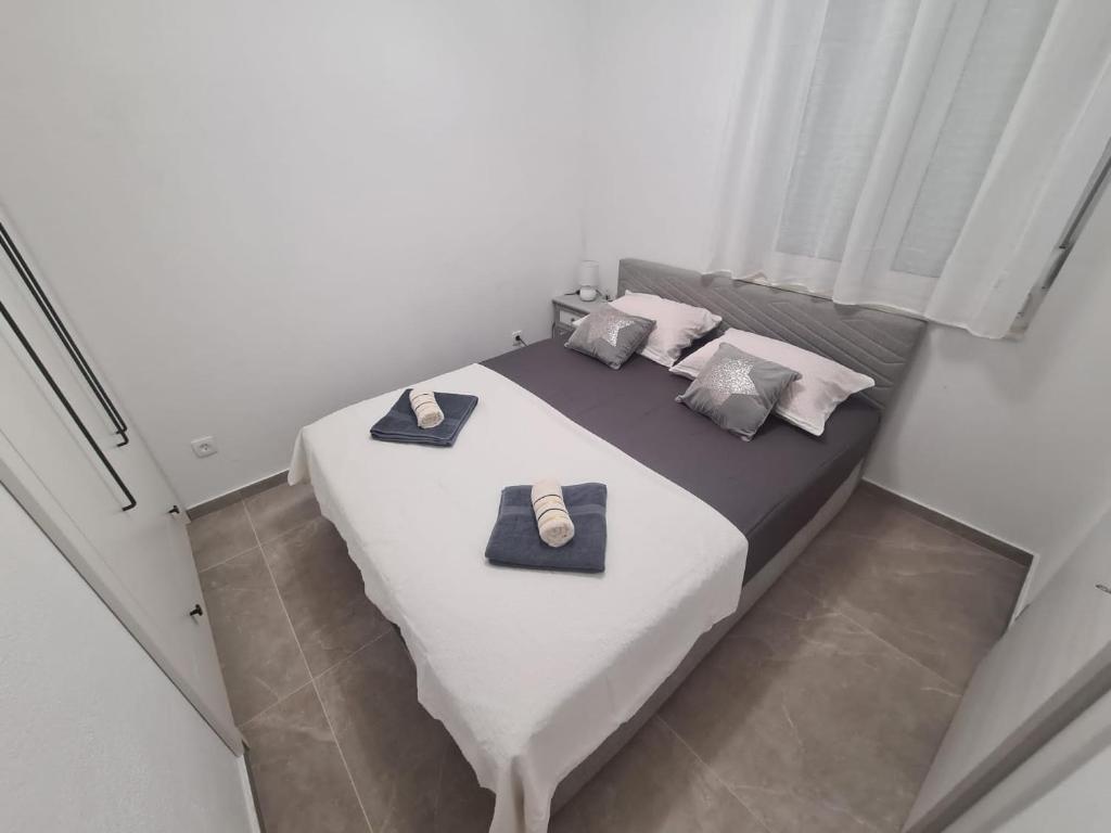 um quarto com uma grande cama branca e 2 almofadas em Lady Di apartments em Kaštela