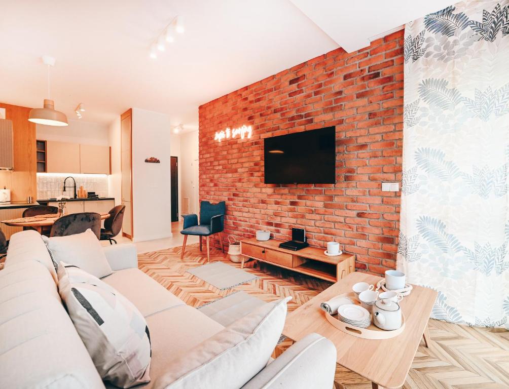 a living room with a couch and a brick wall at Marinero Apartament in Puck