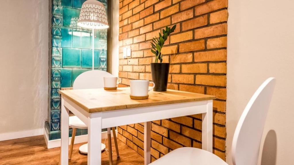 una mesa y sillas en una habitación con una pared de ladrillo en Flamingo Premium Hostel en Cracovia