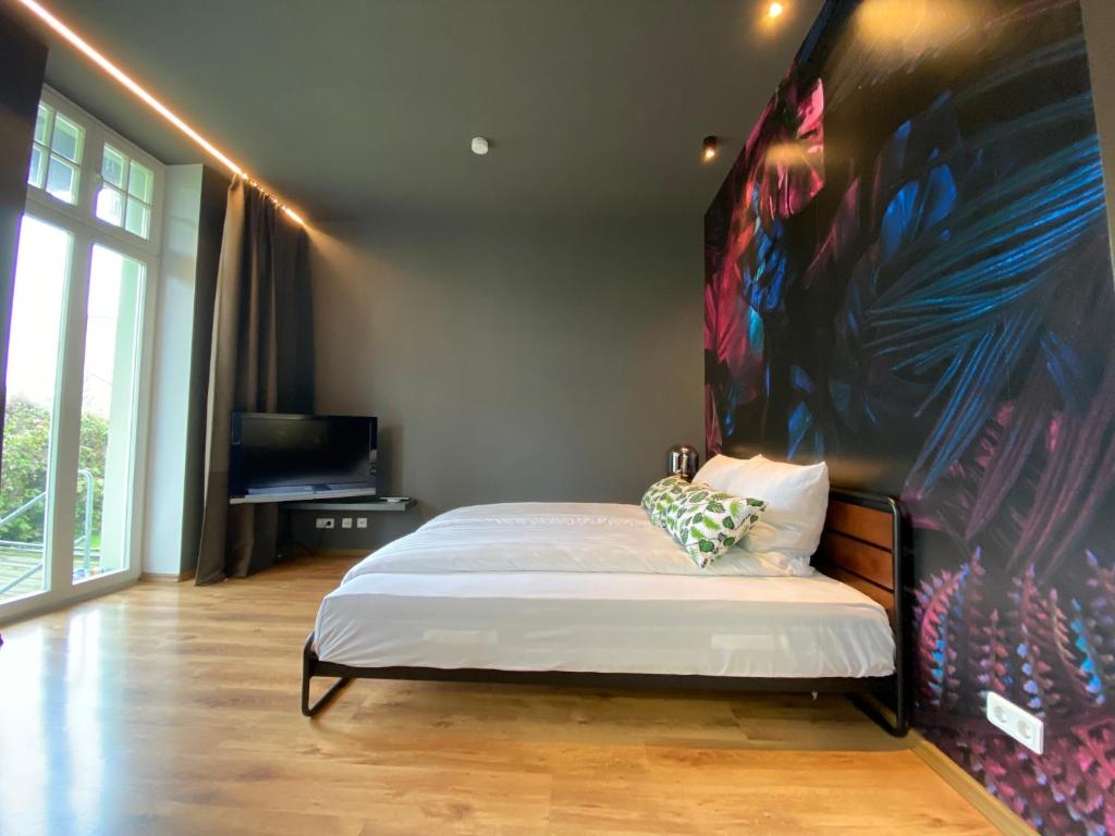 ein Schlafzimmer mit einem Bett mit einem großen Gemälde an der Wand in der Unterkunft Tropisches Loft mit privatem Garten in Magdeburg