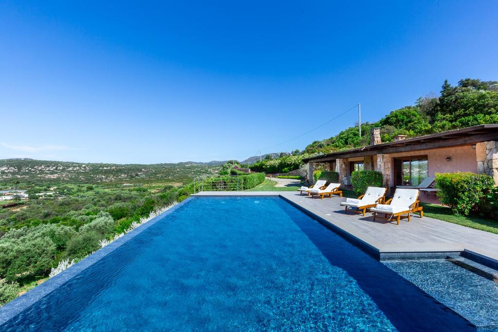 a swimming pool with chairs and a house at Costa Smeralda House in Cugnana