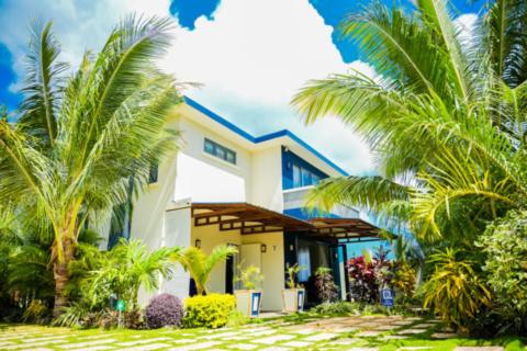 een huis met palmbomen ervoor bij Preety Blue Residence villas in Grand Baie