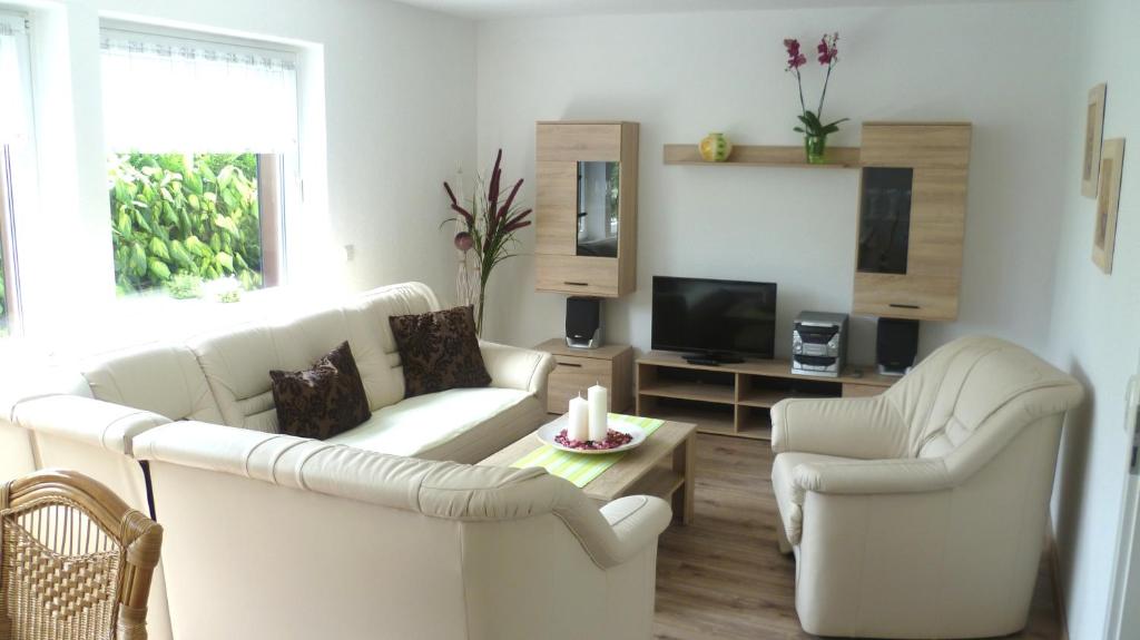 sala de estar con 2 sofás blancos y TV en Ferienhaus Jendral en Blankenburg