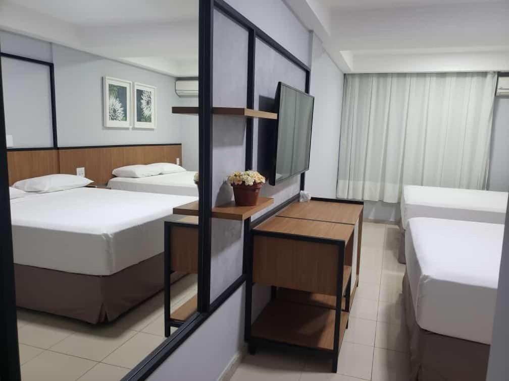 um quarto com 2 camas e uma secretária com uma televisão em Pratti Hotel em Linhares