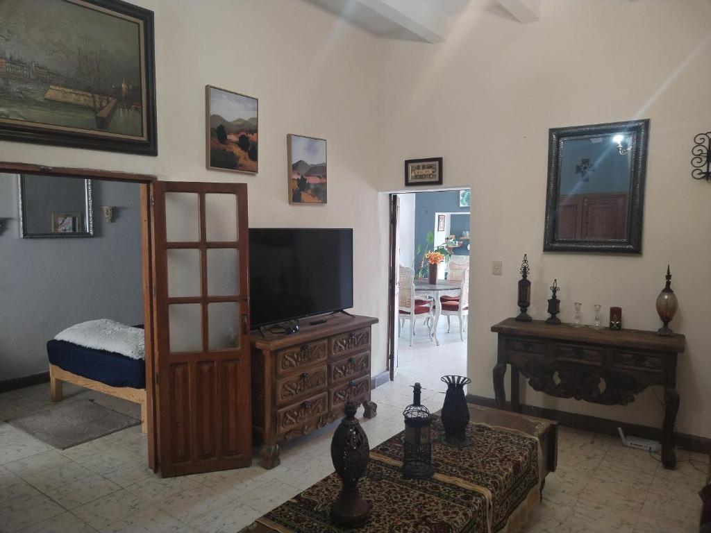 a living room with a flat screen tv and a table at Casa Chelito con Terraza in Guanajuato