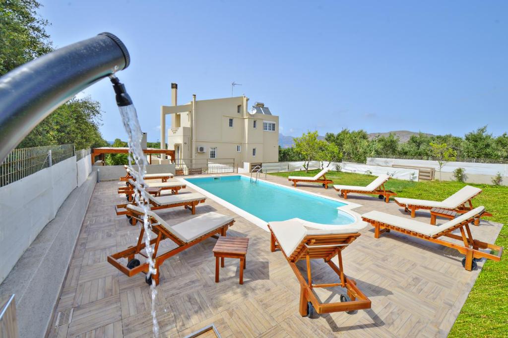 a pool with chairs and a water slide at Dermitzogianni Villa in Kissamos