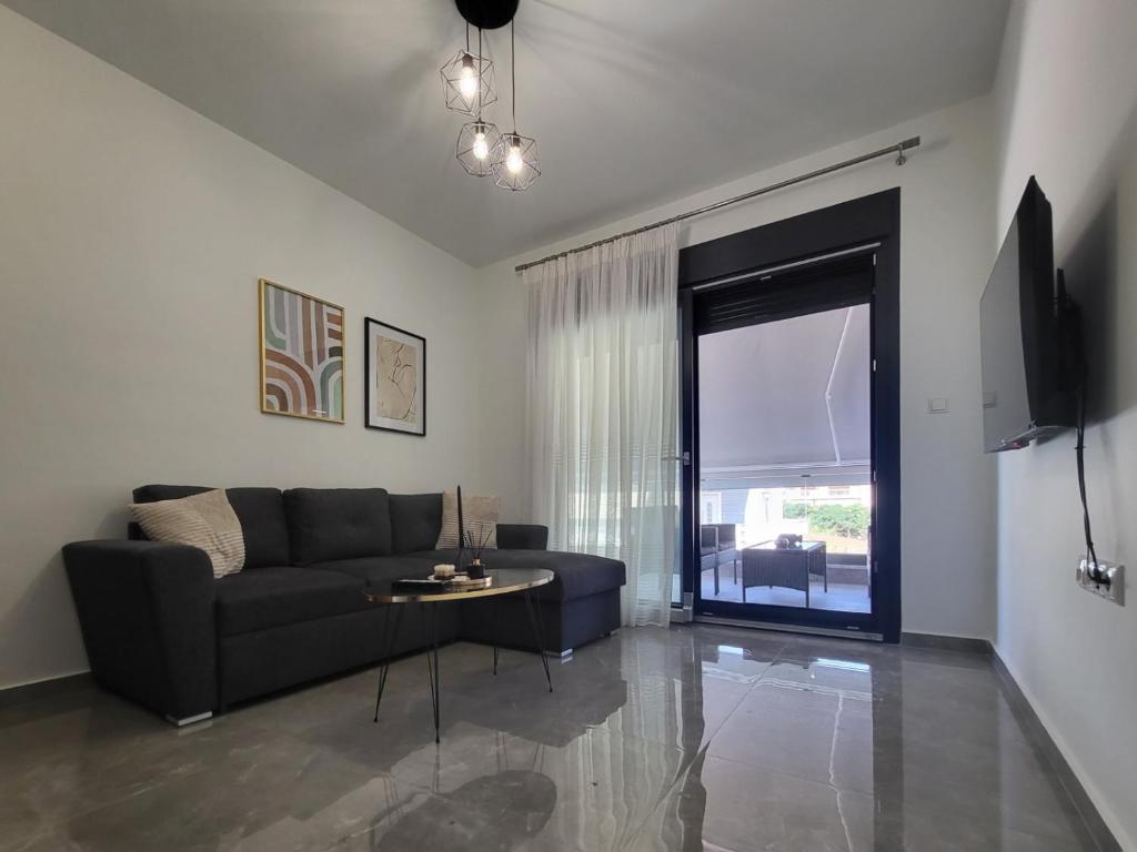 sala de estar con sofá, mesa y ventana en Thἕros Exceptional Residence, en Nea Peramos