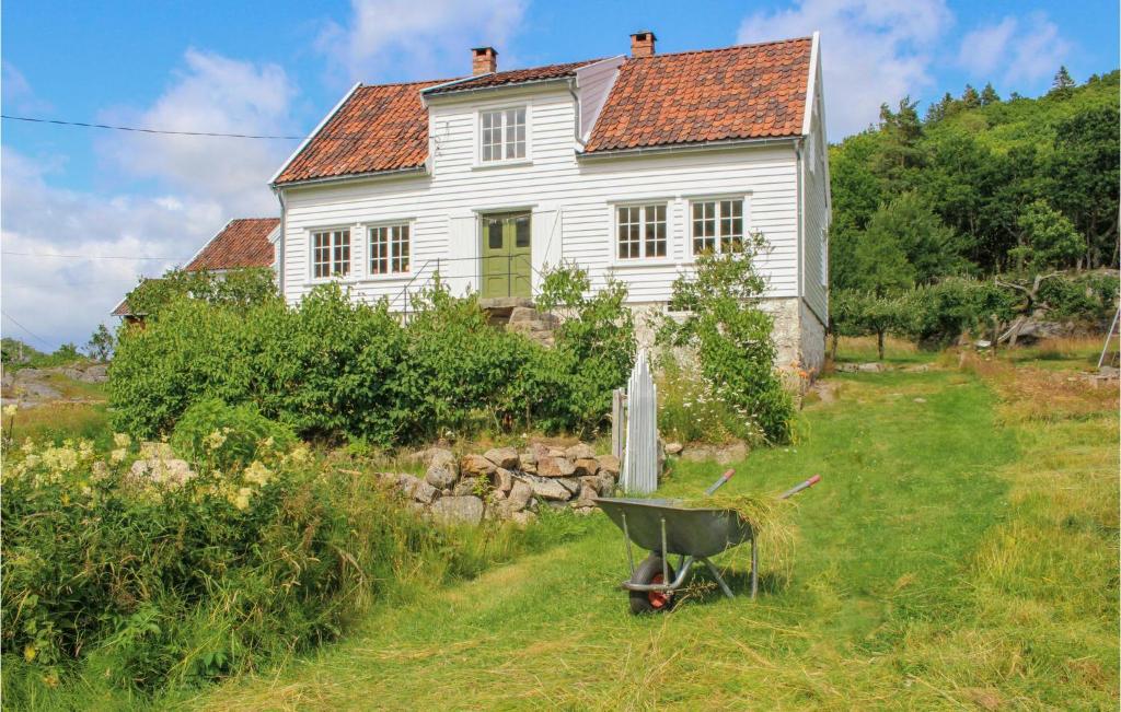 une vieille maison blanche avec une brouette devant elle dans l'établissement Awesome Home In Farsund With House Sea View, à Farsund