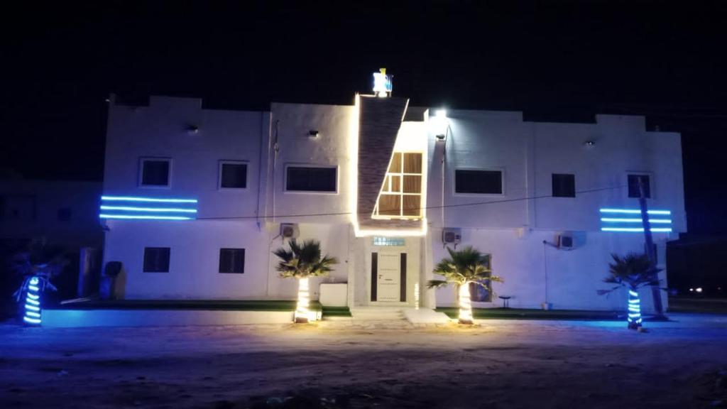 Un bâtiment blanc avec des lumières allumées la nuit dans l'établissement Nouakchott INN, à Nouakchott