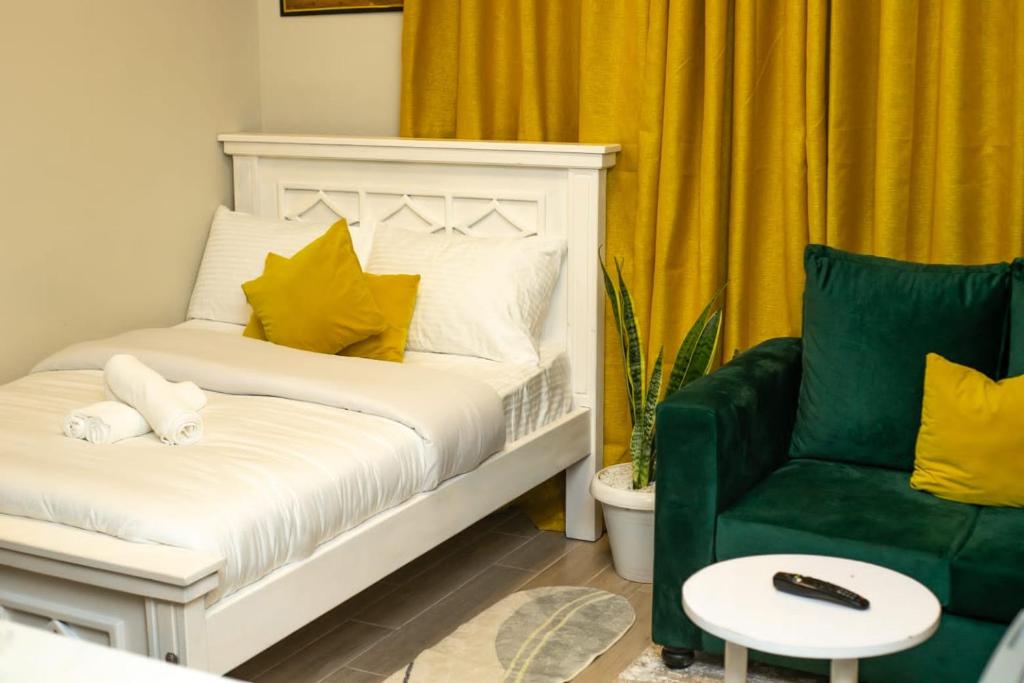 a bedroom with a white bed and a green chair at Indesign Makumbi park studio Apartment D4-5,Syokimau in Syokimau