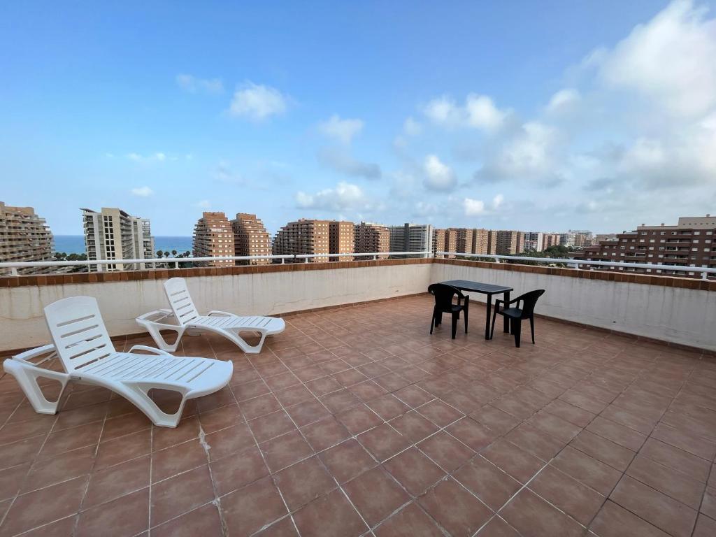 a patio with two chairs and a table on a roof at ACV - Torremar-2ª linea planta 7 Frontal in Oropesa del Mar