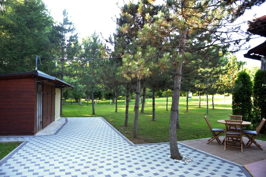 a patio with a table and chairs in a park at Kuća za odmor Čanić gaj in Gospić