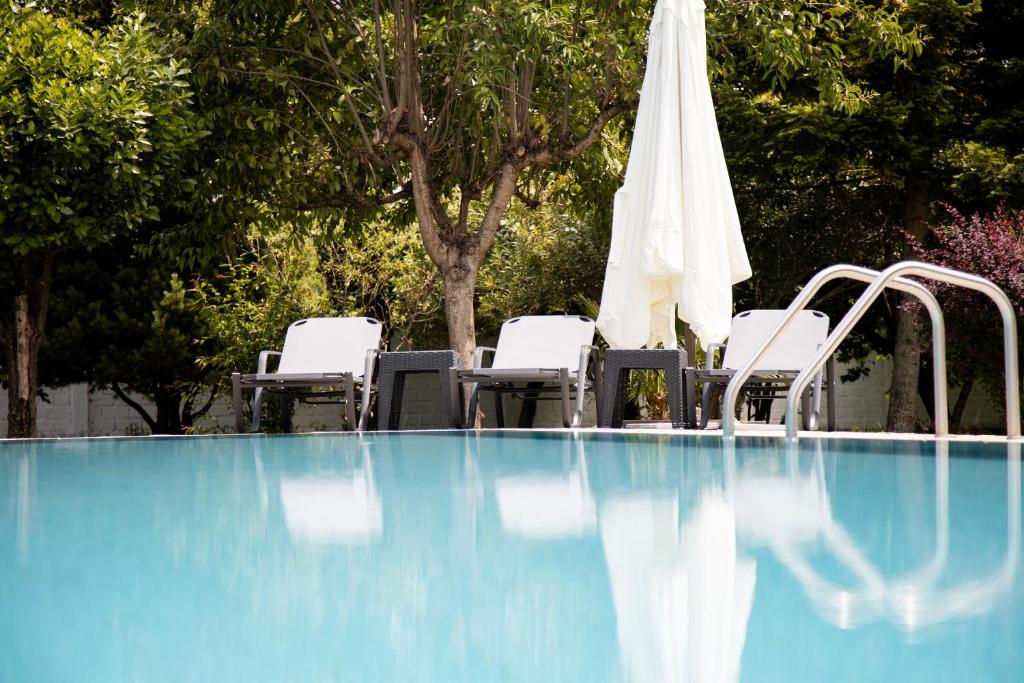 - une piscine avec des chaises et un parasol blanc dans l'établissement Zeusplace PoolVilla Natura, à Kateríni