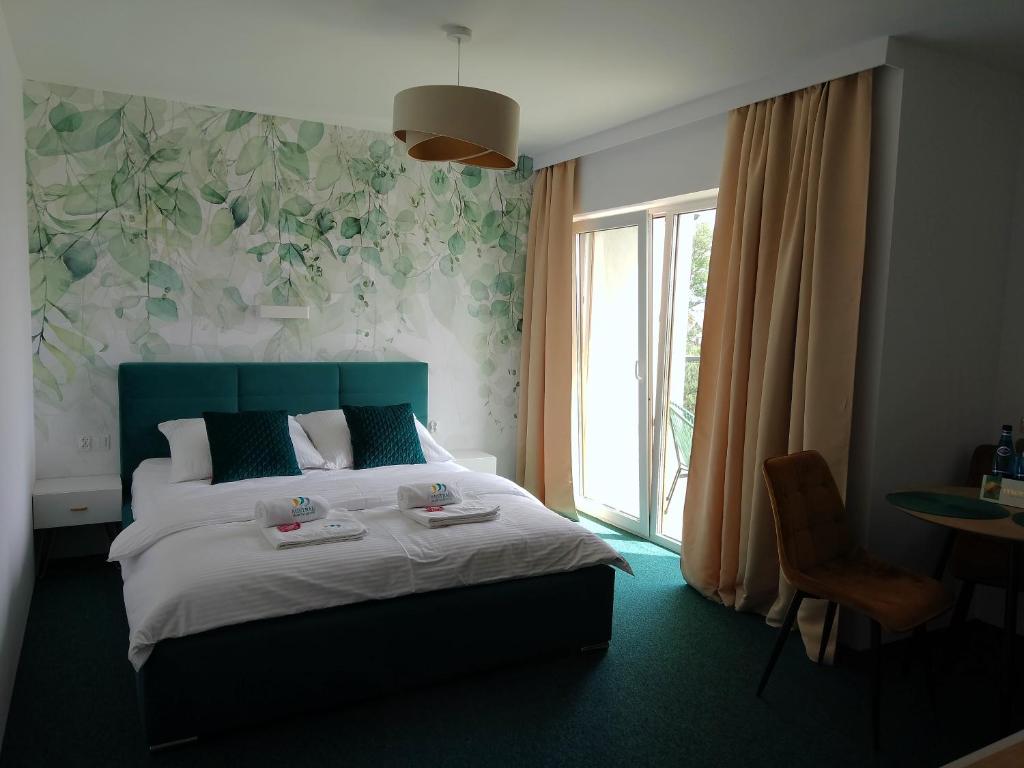 sypialnia z łóżkiem z zielonym zagłówkiem i oknem w obiekcie Apartamenty Mistral w Jastarni