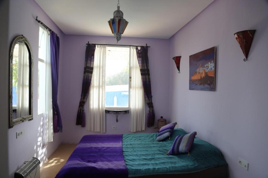- une chambre avec un lit doté de draps violets et une fenêtre dans l'établissement Villa aloe vera, à Essaouira