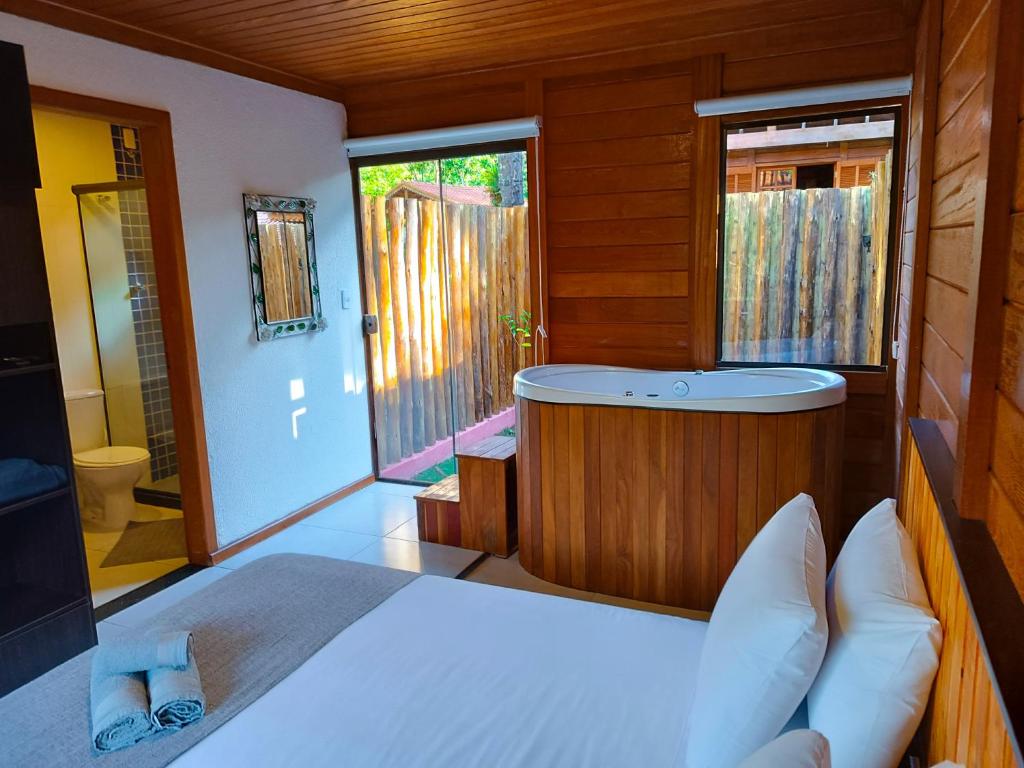 ein Schlafzimmer mit einer Badewanne und einem Bett in einem Zimmer in der Unterkunft Refúgio Allamanda Flats in Visconde De Maua