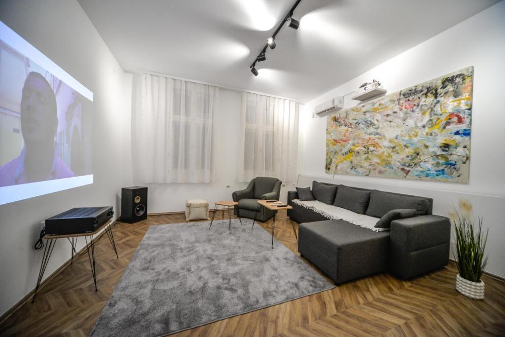 a living room with a couch and a painting on the wall at Apartman Lux in Pirot