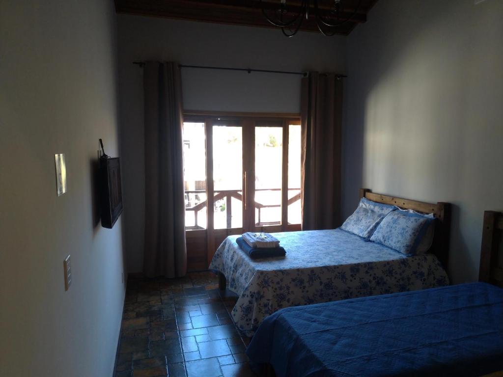 1 Schlafzimmer mit 2 Betten und einem Fenster in der Unterkunft Hospedagem Caminho do Lago in Cunha
