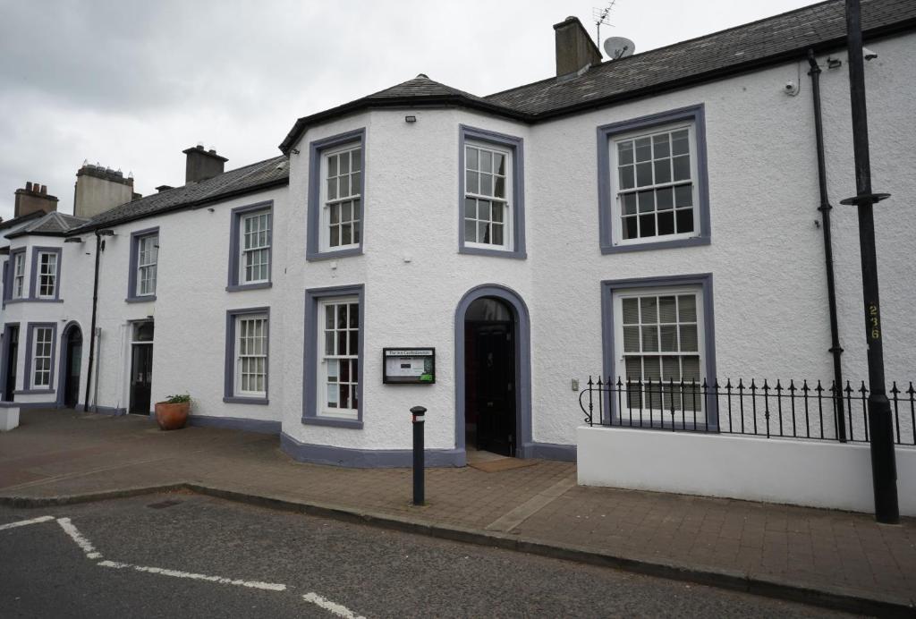 a white building with a black door on a street at The Castledawson Inn in Magherafelt