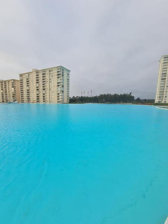 ein großer Pool mit blauem Wasser vor den Gebäuden in der Unterkunft Laguna Bahia in Algarrobo