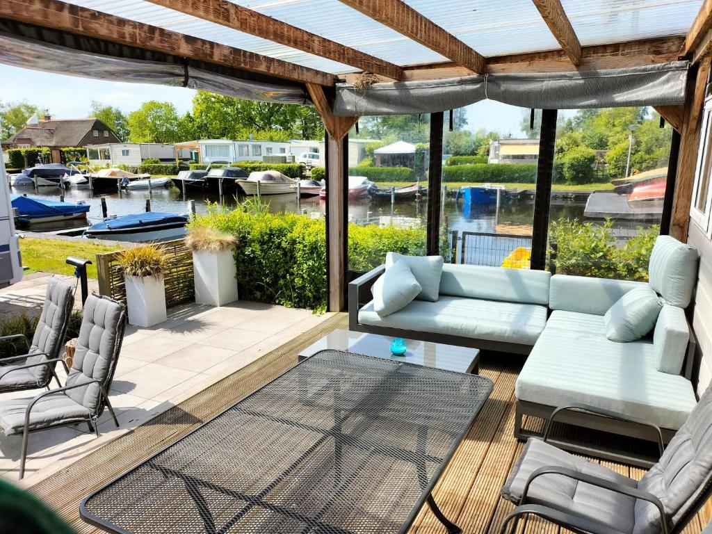 a patio with a couch and a table and chairs at Camping Kleine Belterwijde, Haven Chalet in Belt-Schutsloot