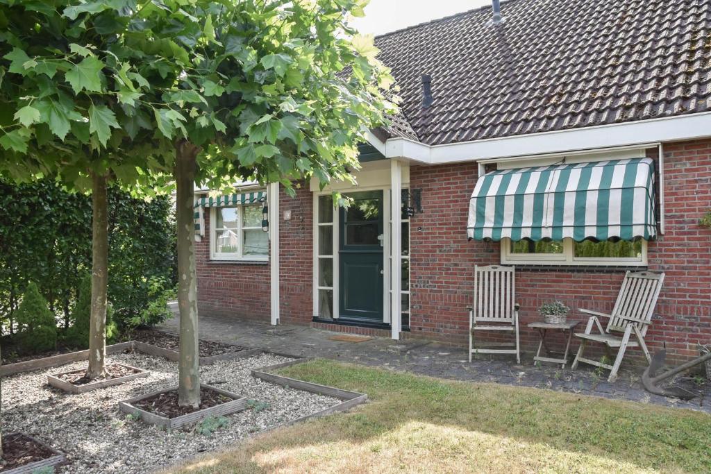 een rood bakstenen huis met een groen en wit zonnescherm bij The Cosy Cottage in Zeewolde