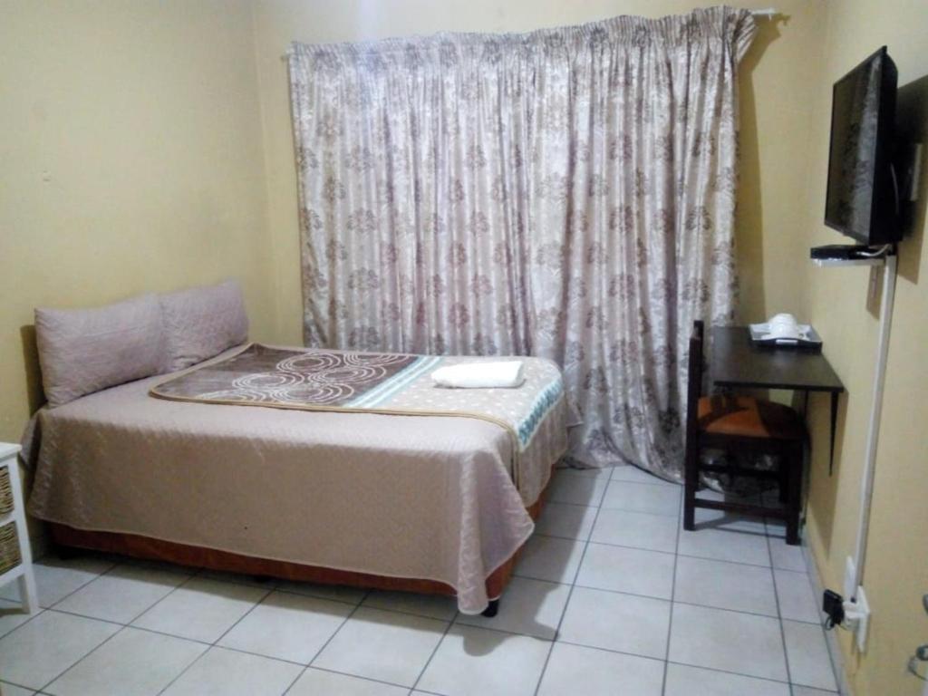 a small bedroom with a bed and a window at MEDUPI 2 Guesthouse. in Kempton Park