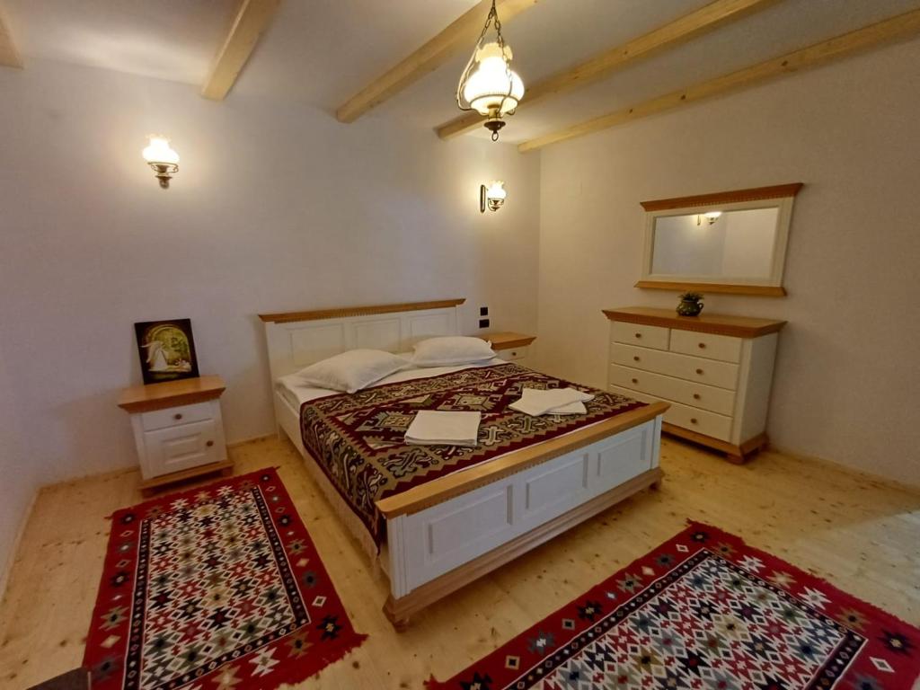 a bedroom with a bed and two rugs at Casuta din Valea Regilor in Grădiştea de Munte