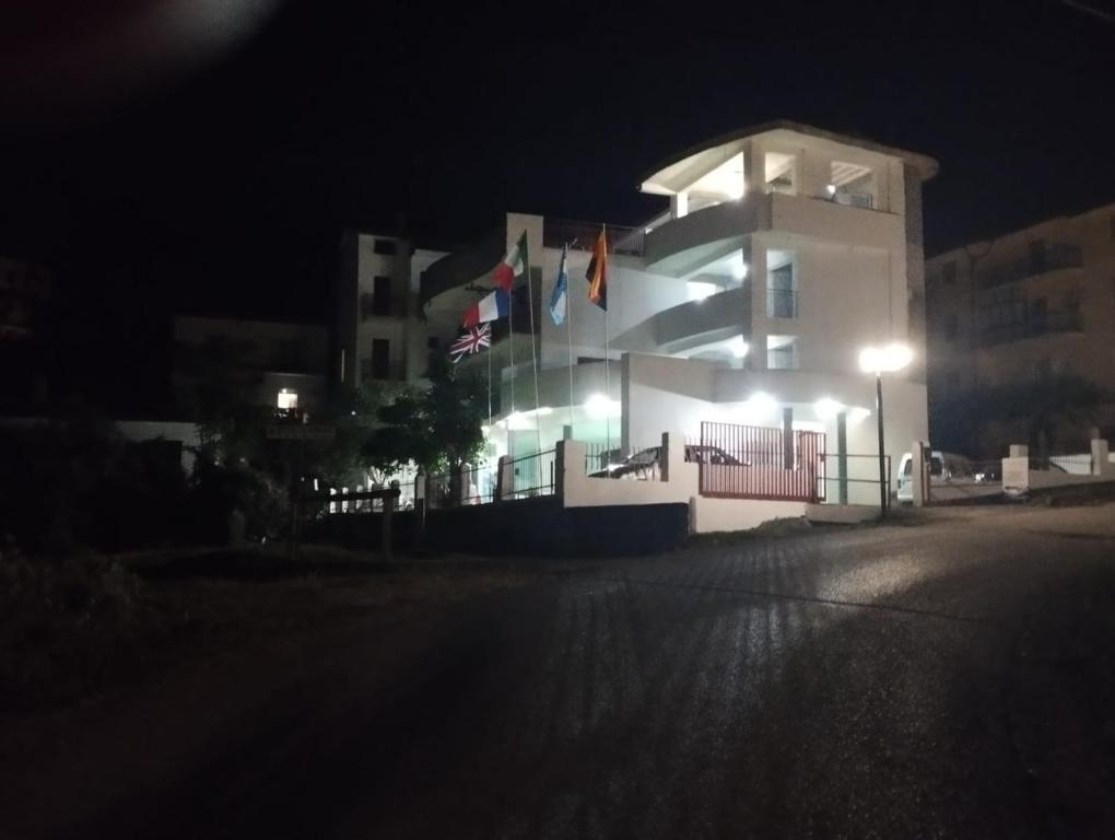 a white building with flags in front of it at night at Luigiane B&B in Acquappesa