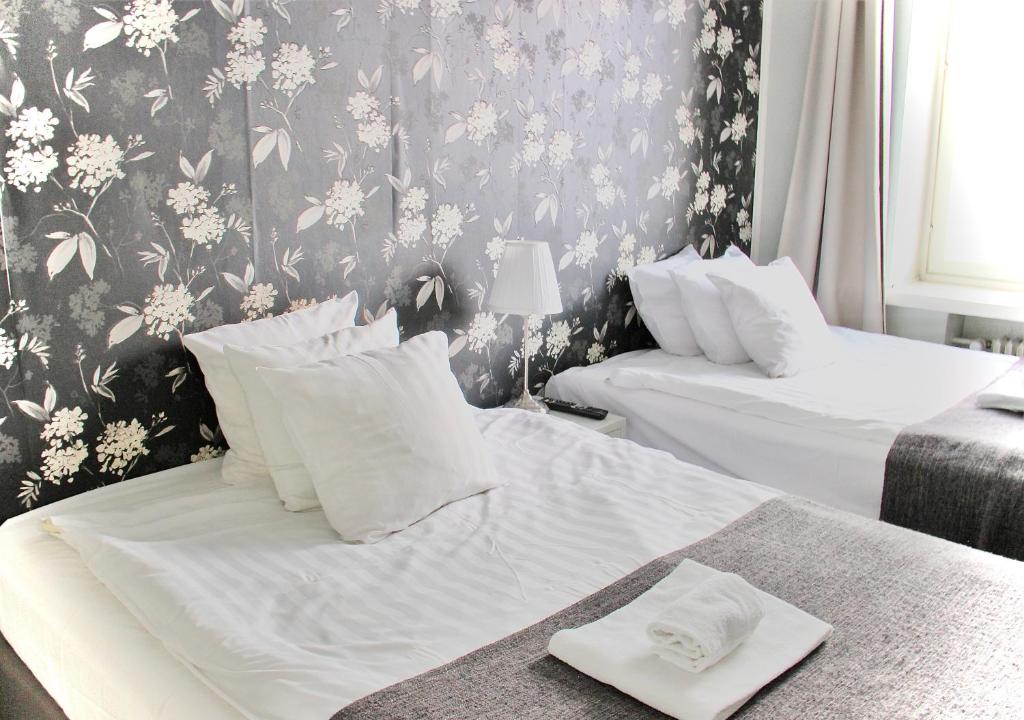 um quarto com 2 camas e um papel de parede floral em Orchidea Kamppi em Helsinque