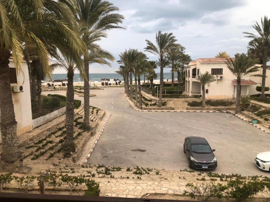 ein Auto auf einem Parkplatz mit Palmen geparkt in der Unterkunft شالية مفروش قرية سما العريش in El Arish