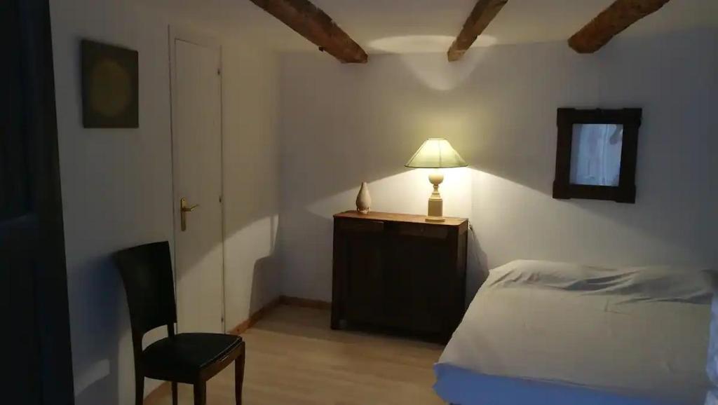 um quarto com uma cama, um candeeiro e uma cadeira em VieuxChateau em Menton