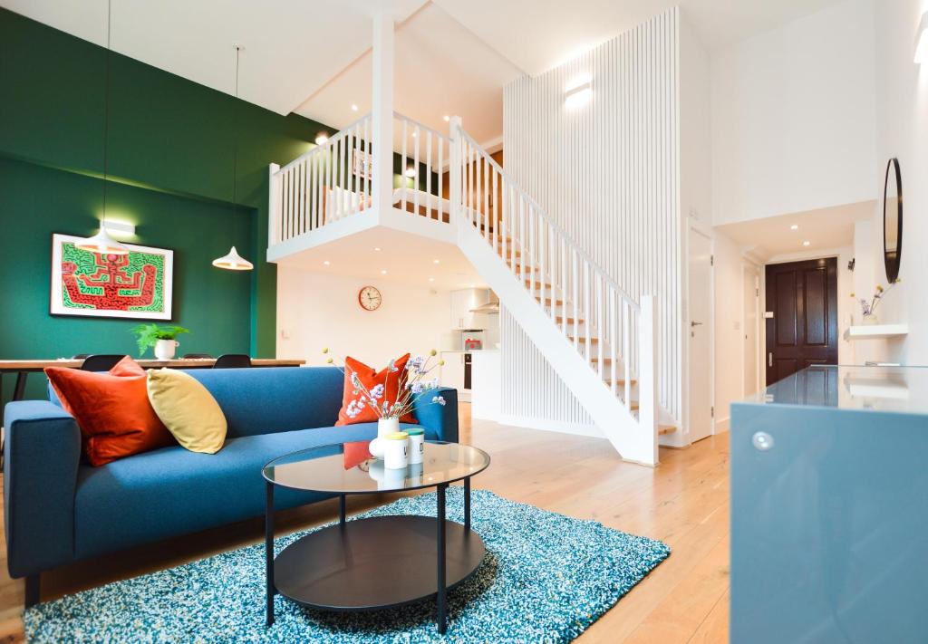 sala de estar con sofá azul y escalera en Spacious West Hampstead Apartment with mezzanine bedroom by Concept Apartments, en Londres