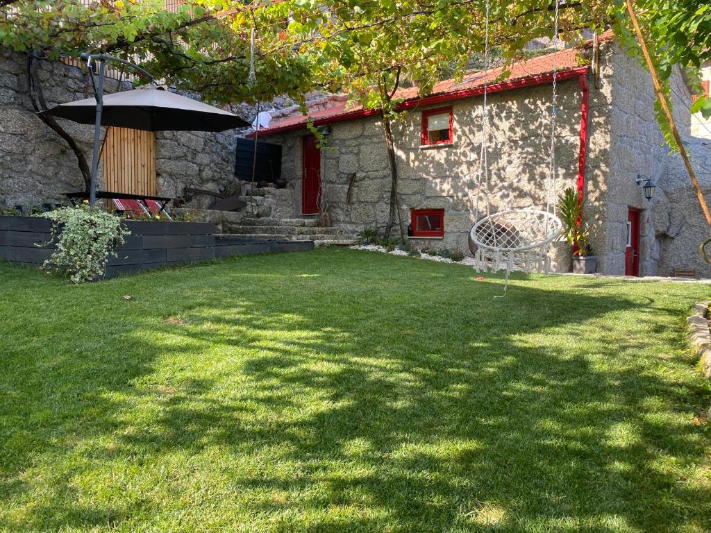 una casa con un patio de césped con sombrilla en Villa Garcia, en Terras de Bouro